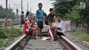 Anak-anak membawa layang-layang di rel kereta api kawasan Jakarta Timur, Kamis (3/1). Minimnya lahan terbuka hijau memaksa anak-anak setempat memilih kawasan rel kereta api sebagai lokasi bermain. (Merdeka.com/Iqbal Nugroho)