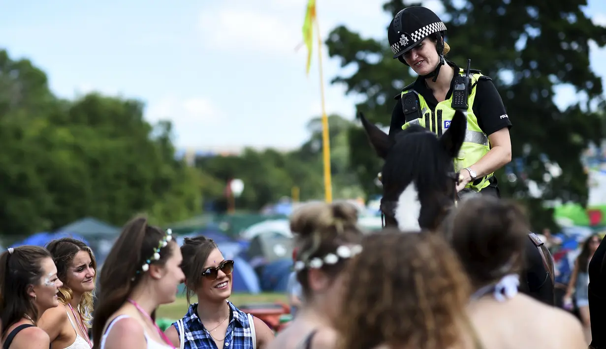 Polisi wanita berkuda yang sedang berpatroli tampak tersenyum kepada peserta Festival Glastonbury di Worthy Farm, Somerset, Inggris, 25 Juni 2015.  (REUTERS/Dylan Martinez) 