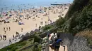 Orang-orang menuruni tangga menuju Pantai Bournemouth, Selatan Inggris pada Selasa 26 Mei 2026, saat kondisi gelombang panas menyebar ke sebagian wilayah tenggara Inggris dan London. (JUSTIN TALLIS/AFP)