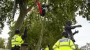 Polisi berpatroli saat aktivis Extinction Rebellion menaiki dua pohon di Parliament Square sebagai bagian dari protes perubahan iklim di London, Inggris, Selasa (8/9/2020). Menggelar aksi di tengah pandemi COVID-19, para aktivis mengenakan masker selama protes berlangsung. (AP Photo/Alberto Pezzali)