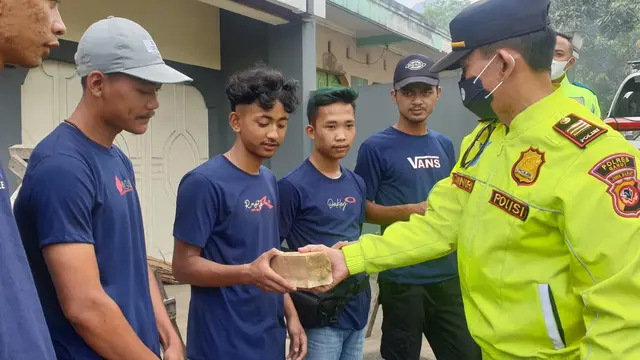 Kapolsek Malangbong AKP Zainuri tengah memberikan secara simbolos beberapa ganjel kayu yang diperuntukan buat pemudik di jalur Tanjakan Andir, Malangbong, Garut. (Liputan6.com/Jayadi Supriadin)