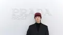 Jaehyun kenakan setelan jas oversized hitam. Dipadukan kaus turtleneck hitam dan topi kupluk rajut merah marun, serta boots hitam [dok. Prada]