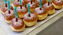 Seorang pekerja memegang nampan berisi berliner (donat Jerman) dengan jarum suntik penuh raspberry jelly di toko roti Kreyenbuhl di Muri, Swiss, 5 Februari 2021. Pembeli dapat menyuntikkan sendiri "vaksin" ke dalam donut dengan pilihan rasa raspberry atau Bailey-liqueur. (STEFAN WERMUTH/AFP)