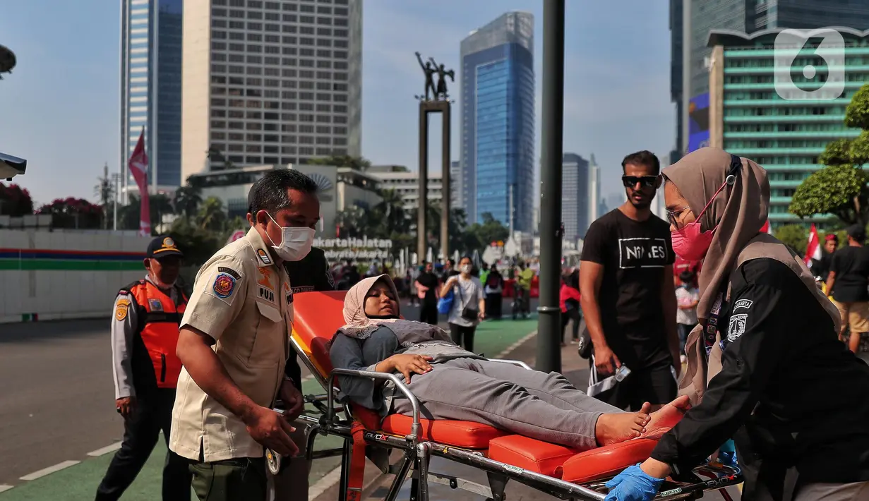 Petugas Dinas Kesehatan DKI Jakarta melakukan evakuasi kepada seorang warga yang mengalami pendarahan karena kelelahan saat CFD di Kawasan Bundaran HI, Jakarta, Minggu (14/8/2022). Warga tersebut langsung mendapatkan penanganan medis dan di bawa ke rumah sakit terdekat. (Liputan6.com/Angga Yuniar)