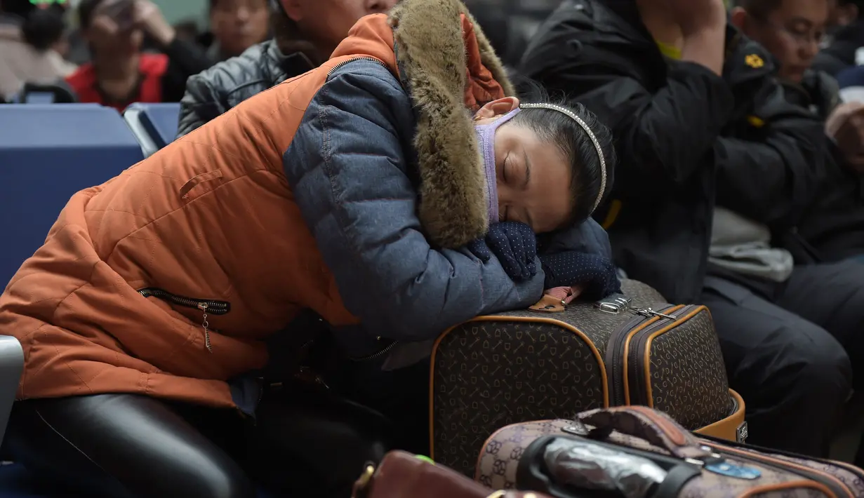 Seorang wanita tertidur saat menungu keberangkatan kereta api di Beijing, China (23/1). Tradisi mudik atau pulang kampung (Chunyun) ini sudah menjadi tradisi tahunan yang turun temurun bagi orang tionghoa. (AFP/Nicolas Asfouri)