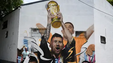 Seniman Maxi Bagnasco berpose di depan muralnya yang menggambarkan kapten Argentina dan pemain depan Lionel Messi mengangkat Trofi Piala Dunia 2022 di samping rekan satu timnya setelah memenangkan turnamen Piala Dunia Qatar 2022 di Buenos Aires pada 22 Desember 2022. (AFP/Luis Robayo)