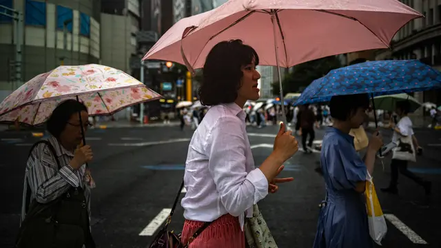 Pejalan kaki berjalan dengan payung mereka di tengah hujan di distrik Ginza Tokyo pada 13 Agustus 2023, saat Topan Lan menuju pulau utama Jepang Honshu.