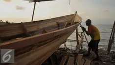 Pekerja mengebor kayu untuk pembuatan kapal kayu berjenis But Tempel di Cilincing, Jakarta, Selasa (9/8). Mahalnya harga kapal kayu berjenis But Tempel dikarenakan mahalnya harga kayu sebagai bahan baku utama. (Liputan6.com/Gempur M Surya)