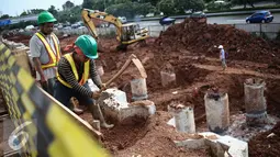 Pekerja mencangkul tanah di proyek pembangunan jalur LRT seksi Cawang-Cibubur, Jakarta, Kamis (8/12). Jalur LRT ini nantinya akan digunakan sebagai salah satu transportasi dalam pelaksanaan Asian Games 2018 .(Liputan6.com/Faizal Fanani)