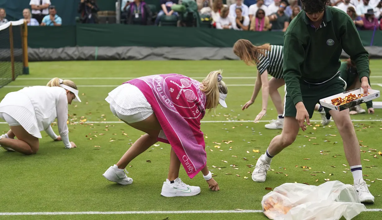 Kedua petenis membantu membersihkan lapangan setelah pemrotes tersebut diusir. (Adam Davy/PA via AP)