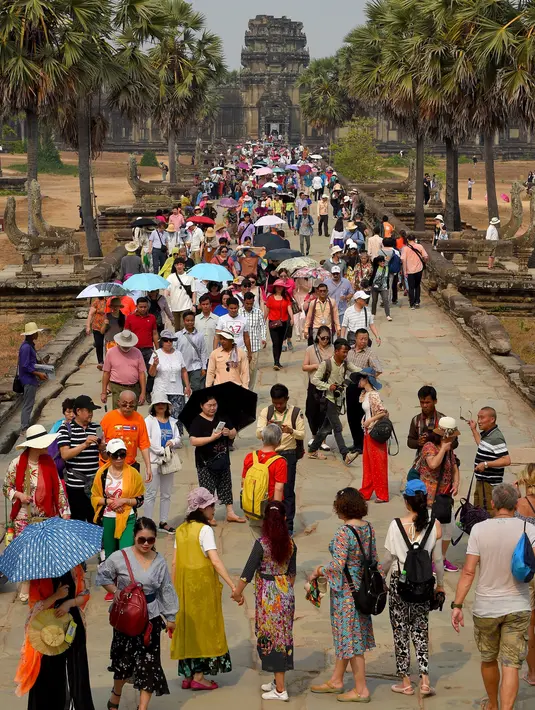 Turis mengunjungi candi Angkor Wat di provinsi Siem Reap, barat laut Kamboja pada 16 Maret 2019. Angkor Wat dibangun pada masa pemerintahan Raja Suryavarman II untuk dipersembahkan pada dewa Wisnu. (TANG CHHIN Sothy / AFP)