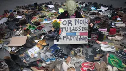 Seorang pria berpakaian seperti Yoda berdiri diantara sepatu yang dipajang di place de la Republique, Prancis, sebagai tanda solidaritas karena pawai lingkungan di Paris dibatalkan jelang KTT Perubahan Iklim, Minggu (29/11).(AFP PHOTO/Joel SAGET)