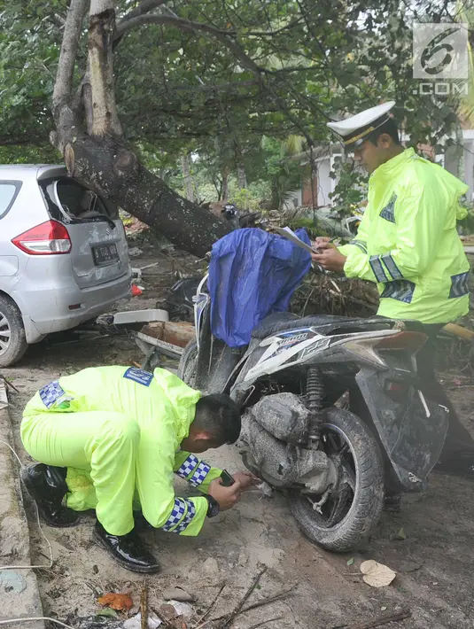 Petugas polisi lalu lintas dari Polres pandeglang melakukan identifikasi kendaraan motor  yang rusak akibat terjangan tsunami di Tanjung Lesung Beach Club, Pandeglang, Banten, selasa (25/12). (Merdeka.com/Arie Basuki)