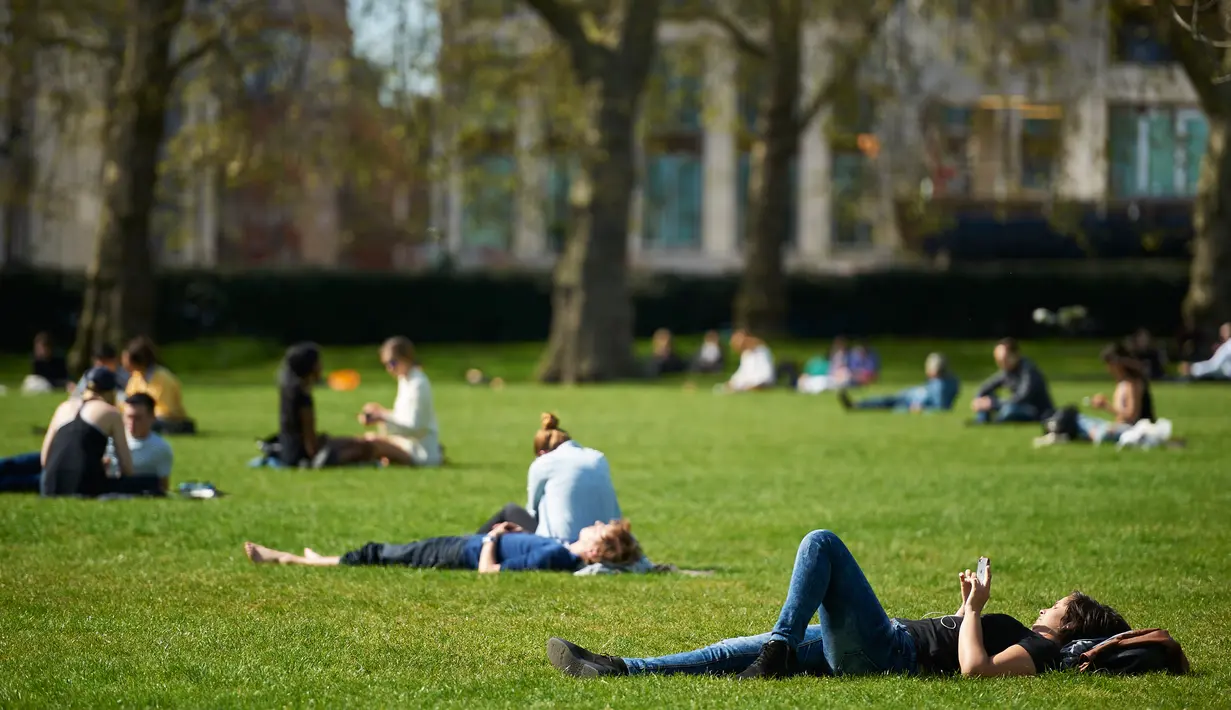 Warga Inggris menikmati sinar matahari sambil bersantai di Green Park, pusat kota London, Rabu (4/5). Awal Mei, suhu udara hangat mulai menyelimuti kota London. (Niklas HALLE'N/AFP)
