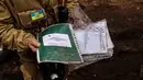 Seorang anggota tentara Ukrania menunjukkan buku catatan Rusia yang ditemukan di kamp pangkalan Rusia yang kosong di dekat Buda-Babynetska, utara Kiev,pada 5 April 2022, beberapa hari setelah pasukan Rusia mundur. (RONALDO SCHEMIDT / AFP)