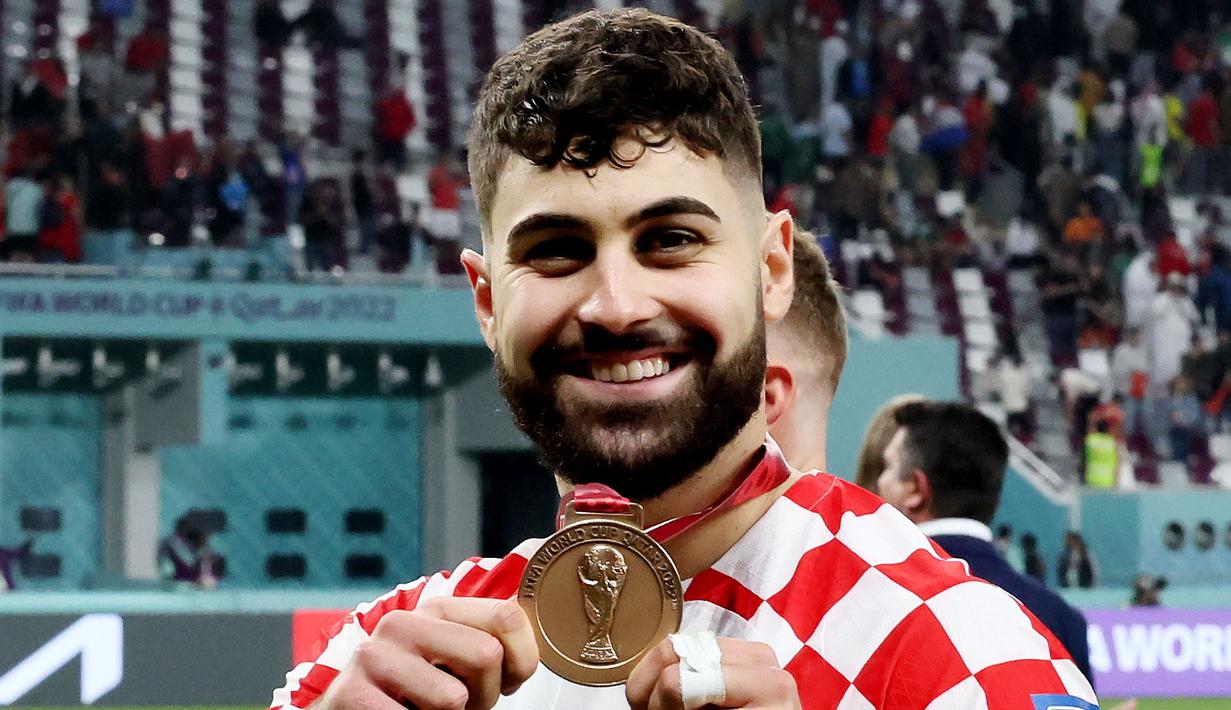 Bek Kroasia, Josko Gvardiol, tersenyum saat menunjukkan medali Piala Dunia 2022 Qatar. (AFP/Jack Guez)