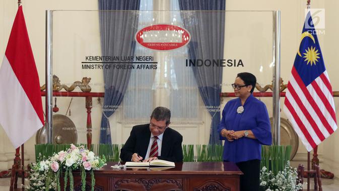 Menteri Luar Negeri Malaysia, Dato' Saifuddin Abdullah (kiri) didampingi Menteri Luar Negeri RI Retno Marsudi menandatangani buku tamu jelang pertemuan  di Gedung Pancasila, Jakarta, Senin (23/7). (Liputan6.com/Helmi Fithriansyah)