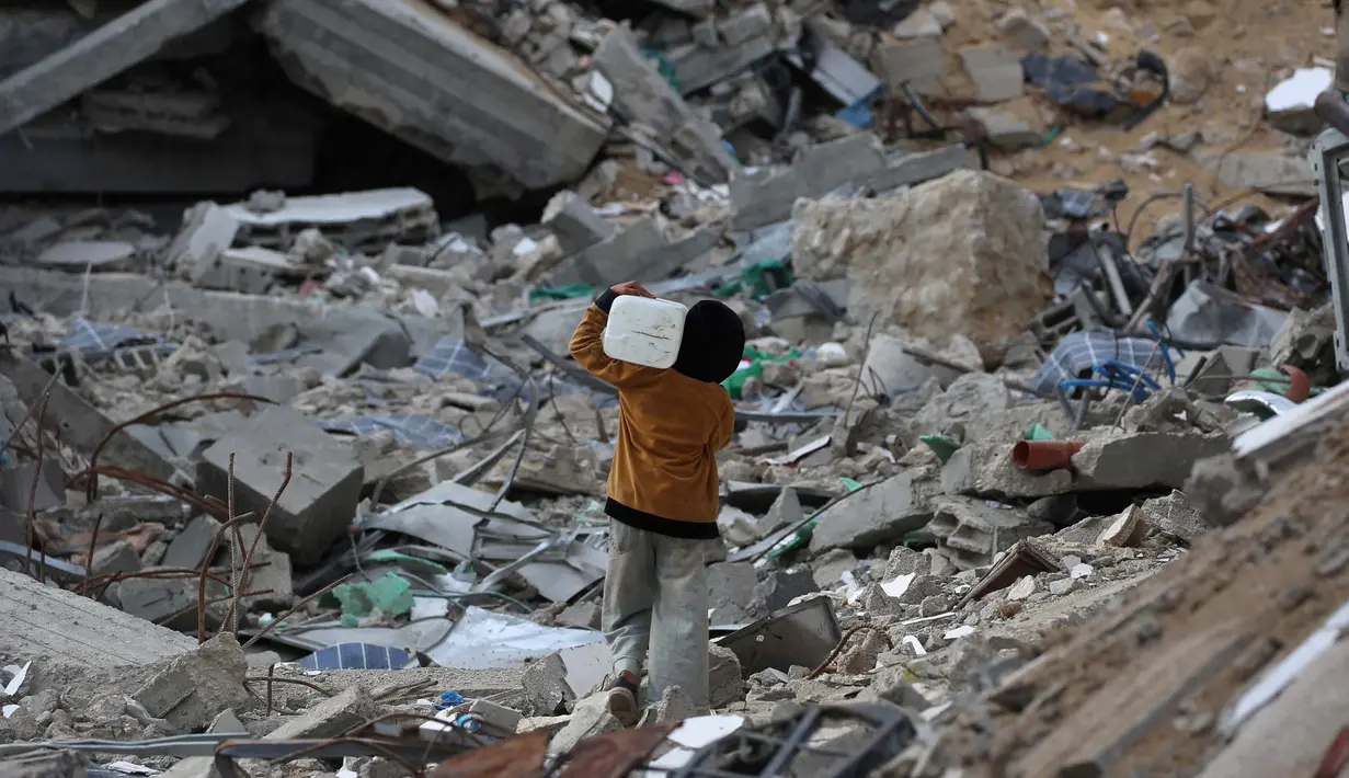<p>Saat ini jutaan anak masih menghadapi masalah-masalah yang sering membuat mereka merasa terancam hingga menimbulkan rasa takut. Tampak dalam foto, seorang anak laki-laki Palestina membawa sebuah wadah plastik saat dia berjalan melewati puing-puing di samping sebuah bangunan yang hancur akibat pemboman Israel baru-baru ini di Khan Yunis di Jalur Gaza selatan pada 19 November 2024. (Eyad BABA/AFP)</p>