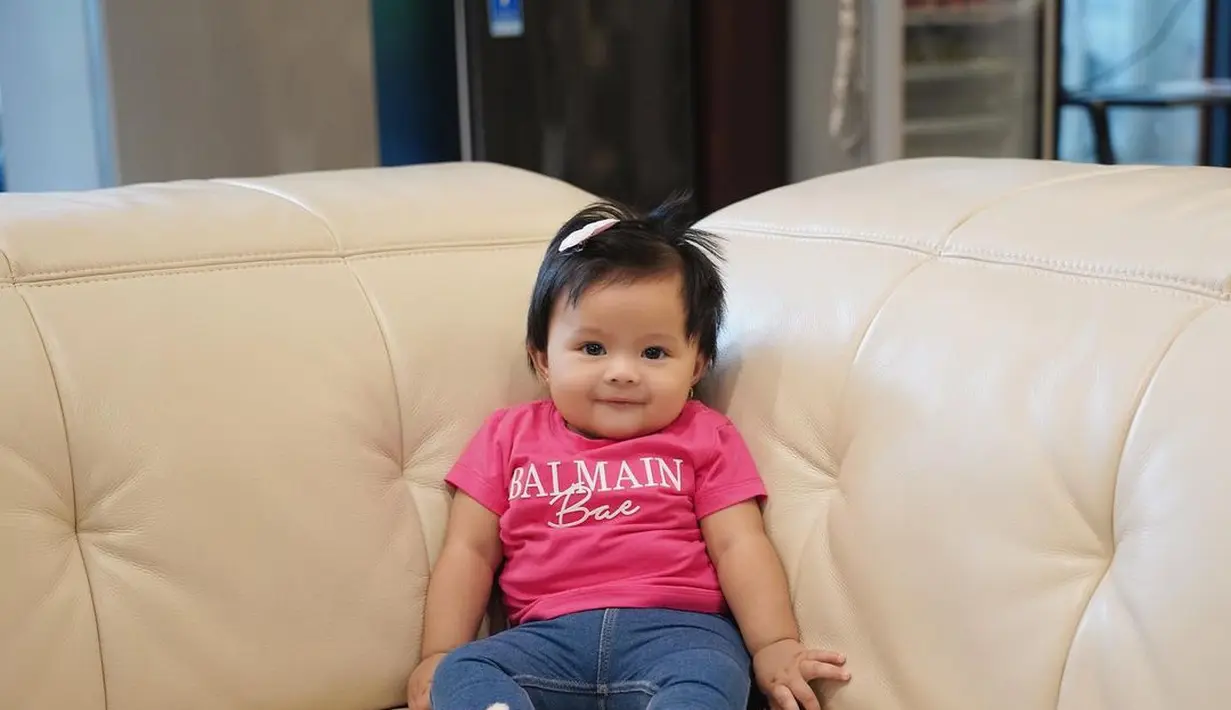 Mengenakan kaos merah muda, Baby Ameena bersandar di sofa. (Foto: Instagram/ ameenaatta)