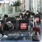 Orang-orang yang mengenakan masker beristirahat di lobi Bandara Internasional Haneda di Tokyo, Senin (28/12/2020). Jepang untuk sementara waktu melarang semua pendatang asing yang bukan penduduk masuk sebagai bentuk antisipasi varian baru COVID-19 hingga akhir Januari 2021. (AP Photo/Koji Sasahara)