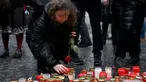 Seorang wanita muda meletakkan lilin dan bunga mawar di tugu peringatan sementara untuk para korban di luar Universitas Charles di pusat kota Praha, pada tanggal 22 Desember 2023. (Michal CIZEK/AFP)
