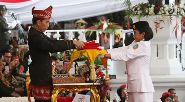Presiden Joko Widodo menerima Bendera Merah Putih oleh anggota Paskibraka, Ruth Celine Eglesya Purba pada Upacara Penurunan Bendera HUT ke-72 Kemerdekaan RI di Halaman Istana Merdeka, Jakarta, Kamis (17/8). (Liputan6.com/Pool)