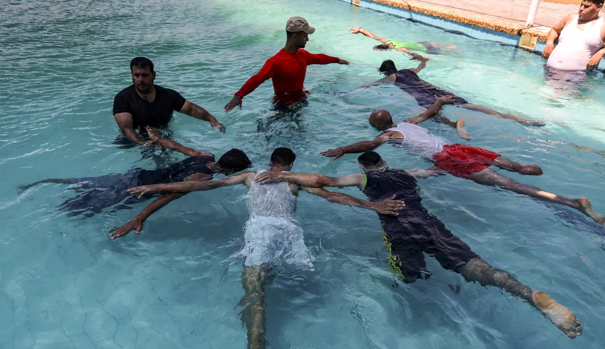 Anak muda Palestina yang diamputasi berlatih di bawah instruksi Majdi al-Tatar (kiri)  di kolam renang Kota Gaza (30/7/2019). Tatar, yang kehilangan kaki kanannya akibat kecelakaan pada masa kecilnya, melatih warga Palestina yang diamputasi selama konflik dengan Israel. (AFP Photo/Mahmud Hams)