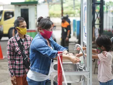 Pengunjung mencuci tangan saat masuk ke kawasan Pasar Minggu, Jakarta, Selasa (23/6/2020). Pascapenutupan tiga hari terkait ditemukannya tiga pedagang yang positif COVID-19, pengunjung Pasar Minggu kini diwajibkan mencuci tangan dan cek suhu tubuh. (Liputan6.com/Immanuel Antonius)