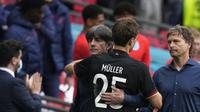 Pelatih Jerman, Joachim Loew, dan Thomas Muller berpelukan setelah kekalahan dari Inggris pada 16 besar Euro 2020 di Stadion Wembley, Selasa (30/6/2021). (Frank Augstein/AFP)