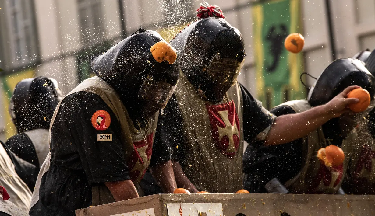 Pasukan penjaga melemparkan jeruk kepada warga sebagai bagian dari tradisi "perang jeruk" selama Karnaval Ivrea di Turin, Italia, Minggu (3/3). Perang Jeruk ini dikenal juga dengan nama Battaglia Delle Arance atau Carnevale d'Ivrea. (MARCO BERTORELLO/AFP)
