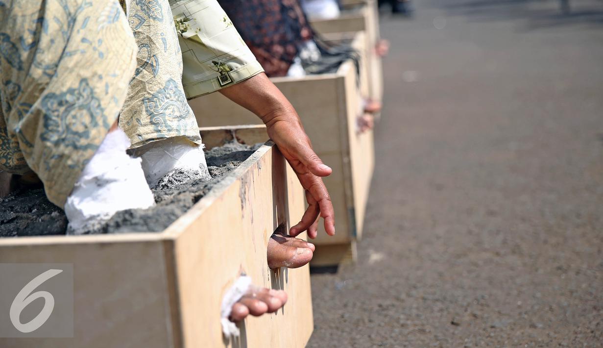Aksi petani mengecor kakinya di depan Istana Negara, Jakarta, Selasa (13/4). Menurut mereka, pembangunan  pabrik semen tersebut dapat mengancam kehidupan petani dan masyarakat. (Liputan6.com/Faizal Fanani)