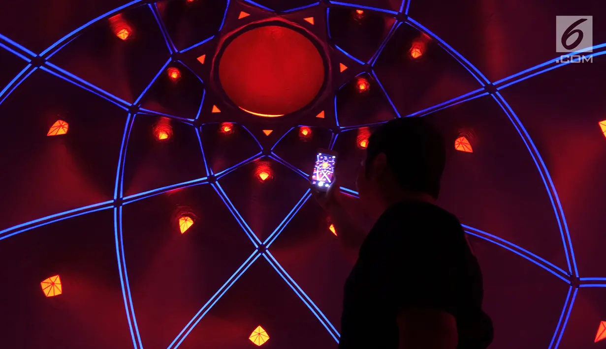 Pengunjung mengambil gambar dalam instalasi seni luminarium kelas dunia atau Trilumin di pusat perbelanjaan Jakarta, Jumat (14/9). Trilumin terinspirasi oleh keindahan geometris alam, juga arsitektur Islam. (Merdeka.com/Imam Buhori)