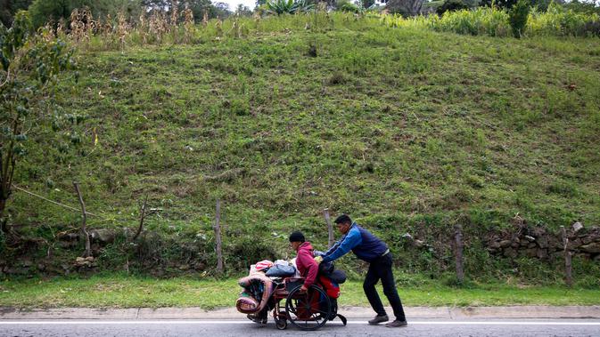 Migran Venezuela, Jefferson Alexis mendorong kursi roda ayahnya, Jose Agustin Lopez di Norte de Santander Department, Kolombia, 15 September 2018. Mereka harus menempuh 600 km dari Venezuela ke Bogota untuk mendapatkan pengobatan. (AFP/SCHNEYDER MENDOZA)