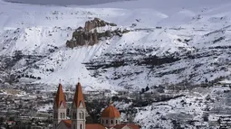 Kota Bcharre yang tertutup salju, menghadap ke lembah Qadisha di gunung Lebanon, di utara ibu kota Beirut (22/2/2022).(AFP/Ibrahim Calhoub)