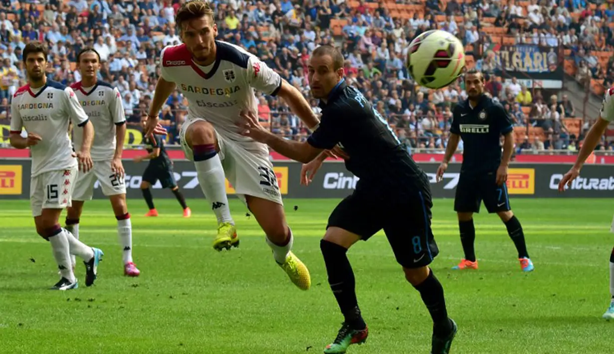 Pemain belakang Cagliari, Luca Ceppitelli (kiri), berusaha membuang bola dari penyerang Inter Milan, Rodrigo Palacio, saat berlaga di Stadion San Siro, Milan, (28/9/2014). Inter Milan kalah 1-4 dari Cagliari. (AFP PHOTO/Giuseppe Cacace)