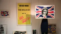 Seniman Inggris, Jamie Reid, menampilkan poster promosi "God Save the Queen" (L), yang dimiliki oleh Sid Vicious, di London pada 12 Oktober 2022, sebagai bagian dari Koleksi Stolper-Wilson yang berisi memorabilia Sex Pistols. Poster ini akan dilelang di Sotheby's di London pada 21 Oktober 2022. Koleksi ini disusun oleh dealer seni kontemporer Paul Stolper dan kritikus serta sejarawan Andrew Wilson. Koleksi ini mengeksplorasi bagaimana Sex Pistols berhasil mengguncang dunia musik dan budaya visual di bawah manajer mereka, Malcolm McLaren, yang mengonsep band ini sebagai bagian dari karya seni yang hidup. (Daniel LEAL / AFP)