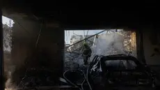 Seorang petugas pemadam kebakaran berjalan melewati dealer mobil yang rusak akibat serangan rudal dan drone besar-besaran Rusia di Kyiv pada Selasa 2 Juni 2026, di tengah invasi Rusia ke Ukraina. (Tetiana DZHAFAROVA/AFP)