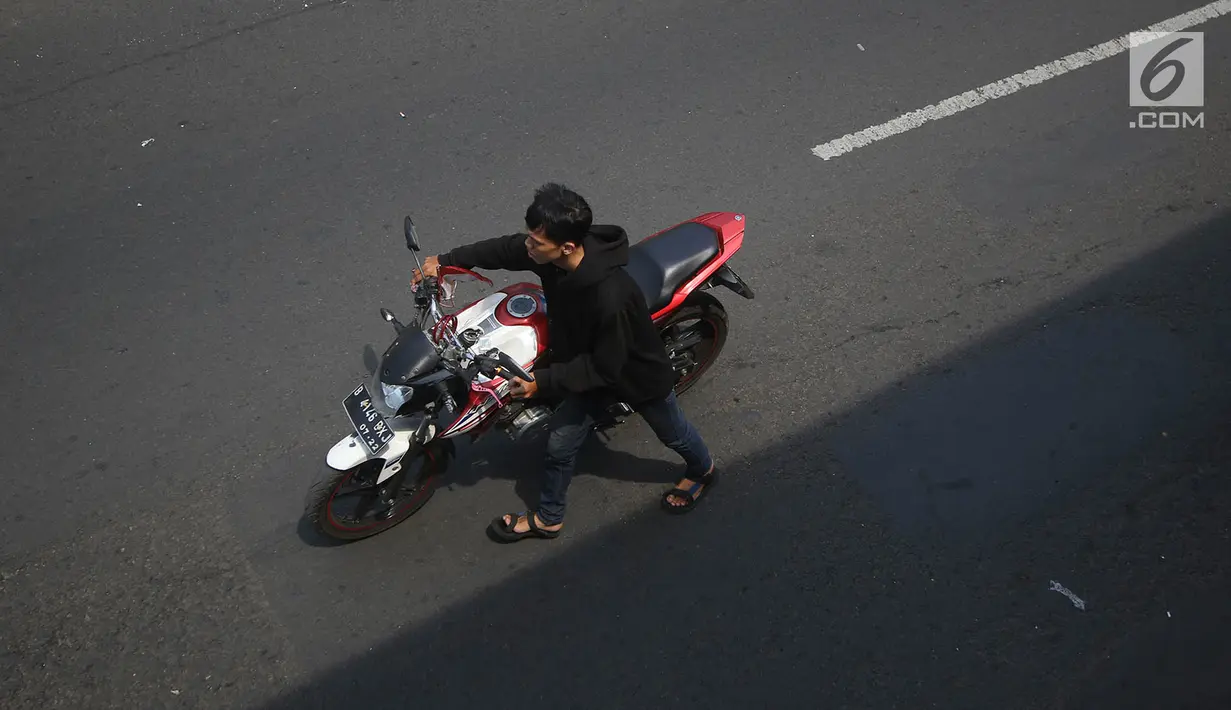 Pengendara mendorong motornya melintasi area Car Free Day Jalan Warung Jati Barat, Jakarta, Minggu (17/9).  Beberapa pengendara motor terlihat bebas menerabas jalan yang dipenuhi orang yang sedang berolahraga dan berjualan (Liputan6.com/Immanuel Antonius)