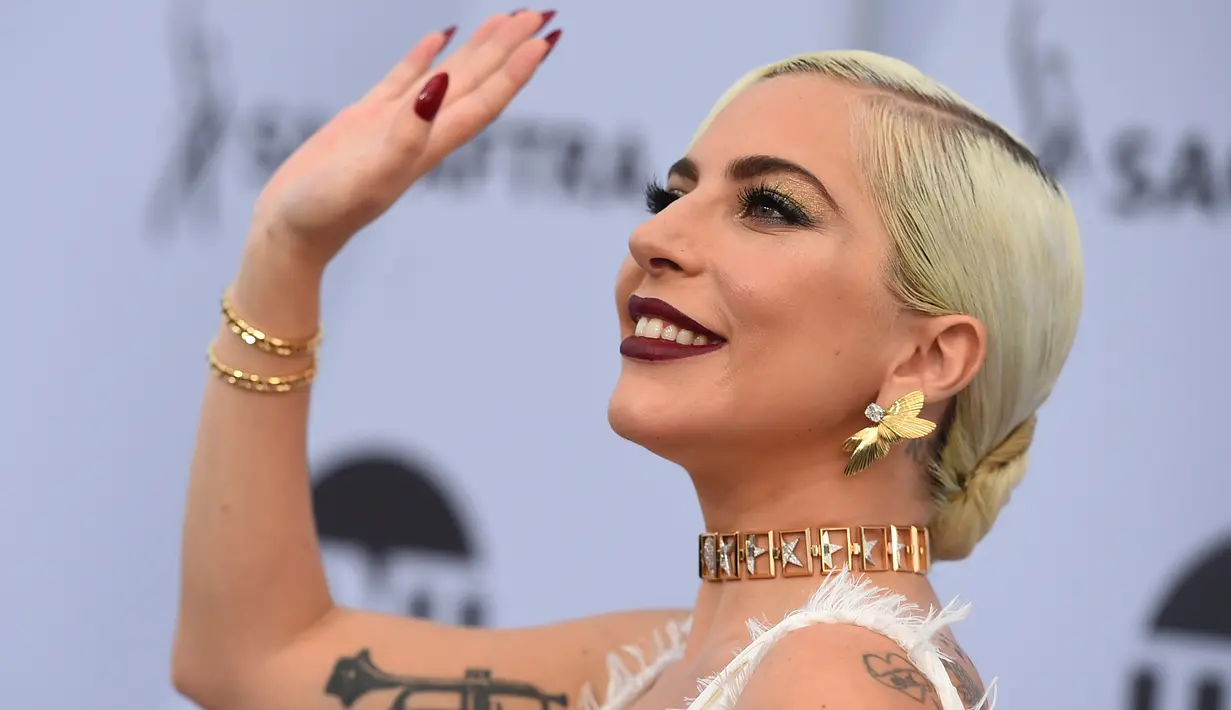 Lady Gaga menyapa penggemar saat menghadiri acara 25th Screen Actors Guild Awards di Los Angeles, California, AS (28/1). Lady Gaga tampil anggun menggenakan gaun putih dengan belahan hingga paha kreasi Dior Haute Couture. (AP Photo/Jordan Strauss)