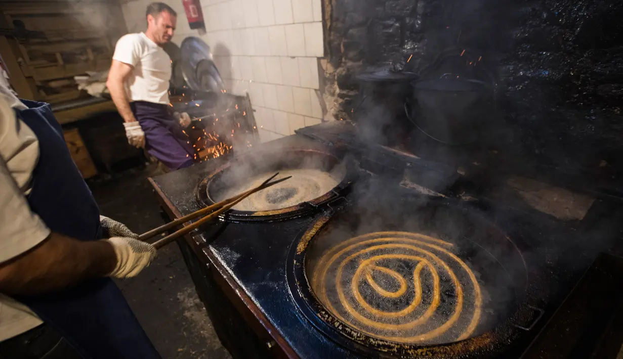 Karyawan menggoreng donat khas Spanyol atau churros dalam minyak panas di restoran dessert tradisional La Manueta, Pamplona, Spanyol, Rabu (10/7/2019). Pastri ringan dan renyah ini cukup populer di daratan Eropa sebagai menu sarapan. (JAIME REINA/AFP)
