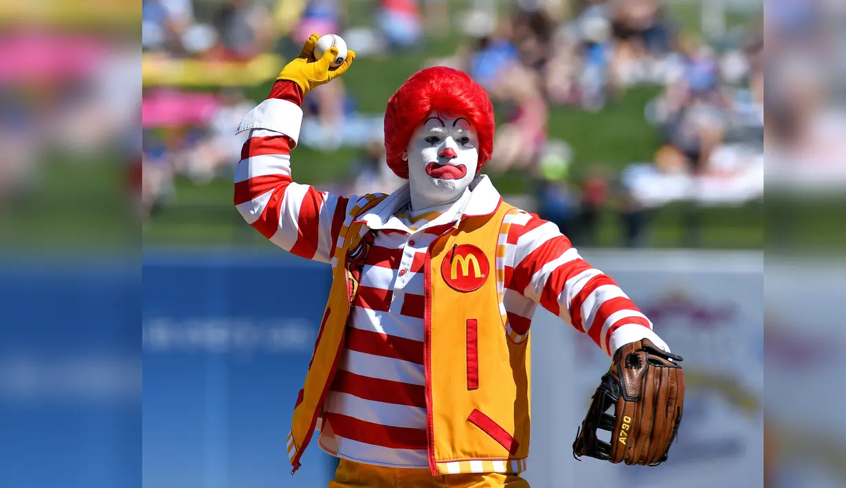 Ronald McDonald bersiap melempar bola saat latihan musim semi bisbol sebelum pertandingan Minggu antara Royals Kansas City dan Los Angeles Dodgers di Surprise, Arizona. (John Sleezer/The Kansas City Star via AP)