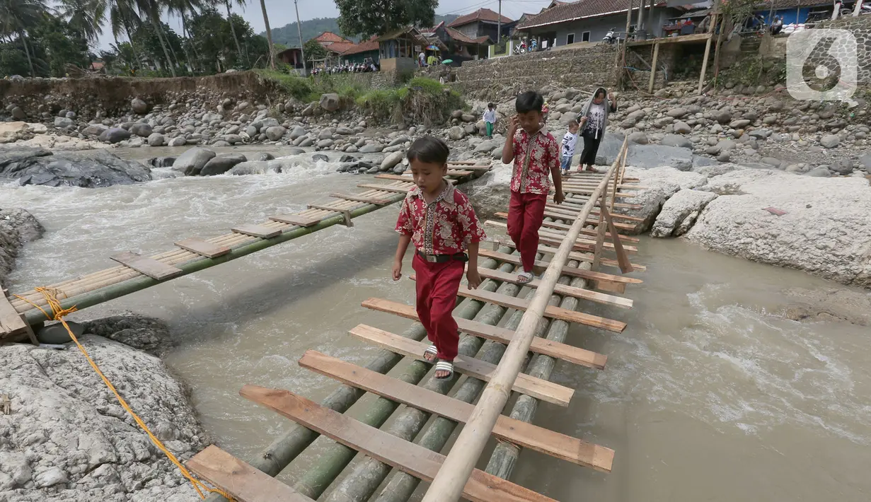 Siswa melintasi jembatan darurat berbahan bambu di Kampung Ciasahan, Desa Sukamaju, Kabupaten Bogor, Kamis (6/2/2020). Pembangunan kembali jembatan Ciasahan yang ambruk akibat banjir bandang pada Rabu (1/1) itu diharapkan mampu memulihkan aktivitas dan perekonomian warga. (merdeka.com/Arie Basuki)