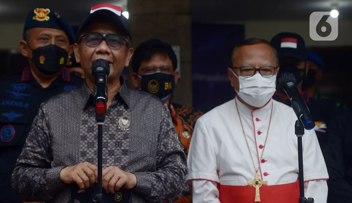 Menteri Koordinator Bidang Politik, Hukum, dan Keamanan (Menko Polhukam) Mahfud MD (kiri) menyampaikan keterangan saat mengunjungi Gereja Katedral, Jakarta, Jumat (24/12/2021). Sebanyak 100 personel diturunkan untuk mengamankan ibadah Natal 2021 Gereja Katedral. (merdeka.com/Imam Buhori)