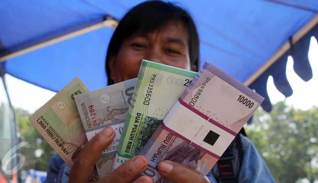 Warga menunjukan uang pecahan Rupiah di layanan mobil kas keliling Bank Indonesia di Lapangan IRTI, Monas, Jakarta, Kamis (2/7). Sebanyak 15 bank membuka gerai penukaran uang pecahan hingga 15 Juli mendatang. (Liputan6com/Helmi Afandi)