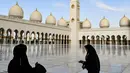 Dua wanita berdiri di halaman Masjid Agung Sheikh Zayed di Abu Dhabi, Uni Emirat Arab. Dibangun dengan 82 kubah bergaya Maroko dan semuanya dihias dengan batu pualam putih. (Photo by Vincenzo PINTO / AFP)