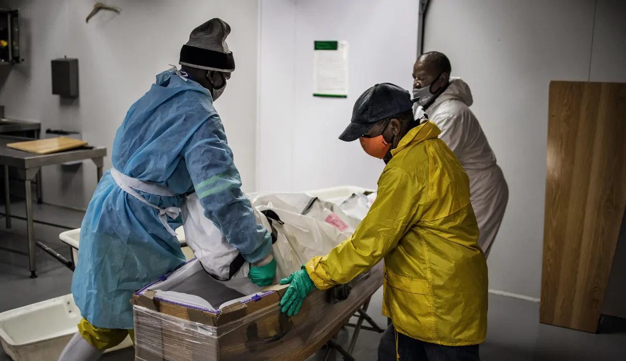 Para pengurus memindahkan jenazah pasien virus corona COVID-19 ke dalam peti mati di rumah duka AVBOB, Soweto, Afrika Selatan, 24 Juli 2020. (MARCO LONGARI/AFP)