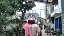 Ondel-ondel berjalan di dekat spanduk peringatan Zona Merah di RW 004, Kelurahan Cipinang Melayu, Kecamatan Makassar Jakarta, Rabu (27/1/2021). Pemprov DKI Jakarta mencatat sebanyak 54 rukun warga (RW) menjadi zona merah Covid-19 per 21 Januari 2021. (merdeka.com/Iqbal S Nugroho)