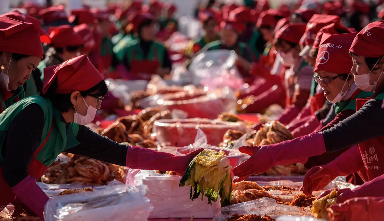 Peserta membuat kimchi, hidangan tradisional Korea Selatan, selama Festival Kimchi tahunan di Seoul (2/11). Hidangan tradisional berupa kubis yang difermentasi dan lobak ini hasilnya akan didonasikan untuk kaum minoritas di Korsel.  (AFP Photo/Ed Jones)