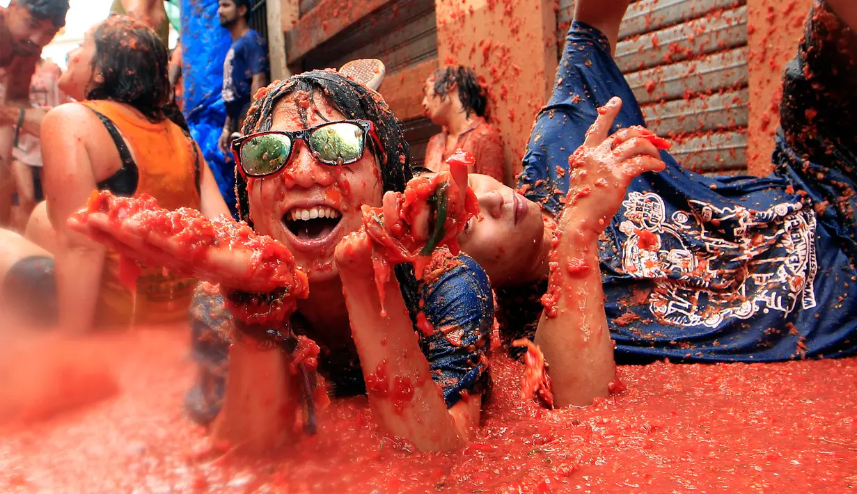 Salah satu peserta menikmati genangan tomat diantara kericuhan festival La Tomatina di desa Bunol, Spanyol, Rabu (30/8). Sekitar 700 petugas keamanan dikerahkan untuk mengawasi festival selama berlangsung. (Alberto Saiz/AP)