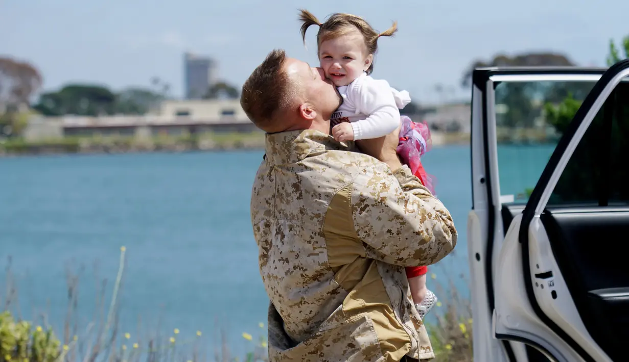 Seorang Angkatan Laut AS memeluk anaknya saat tiba di Camp Pendleton di Oceanside, California, AS, Kamis (11/5). Unit Ekspedisi Kelautan 11  telah menjalani tugas ke sejumlah negara selama 7 bulan. (AFP/ Sandy Huffaker)